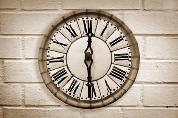 Vintage retro style clock on a white brick wall, sepia process