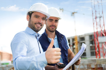 Engineer and worker watching blueprint on construction site