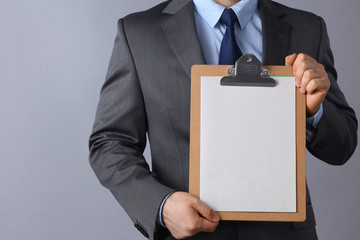 Young man standing with folder, isolated on gray background