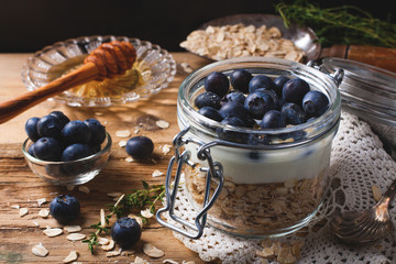 Muesli with yogurt and blue berries in glass jar.