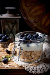 Muesli with yogurt and blue berries in glass jar.