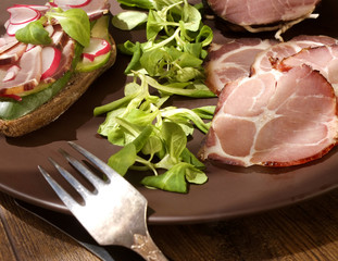 Crude, dried, organic gammon ham with sandwich and salad on plate