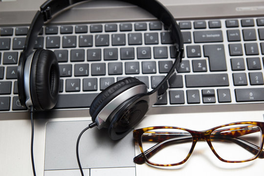 Headphones on laptop with eyeglasses