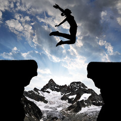 Silhouette the girl jumping over the gap at sunset.