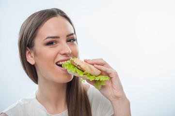 Cheerful young girl is biting unhealthy food