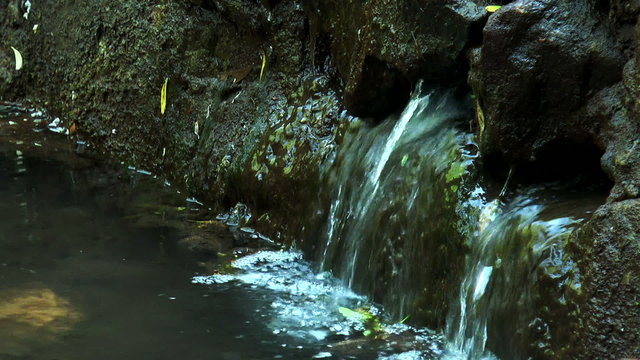 Water Falling Out Of Multiple Holes In a Rock Of a Natural Water Source 