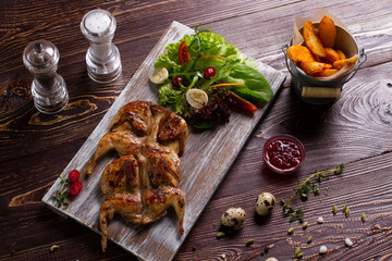 Roasted quail with salad and potatoes.