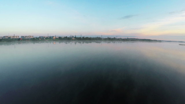 Flying over the misty lake at dawn - aerial survey