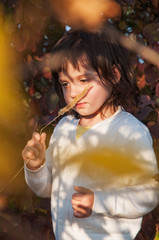 Dreamy little girl keep stalk of grass near the nose