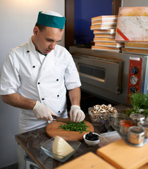 Chef in  kitchen cut parsley pizza