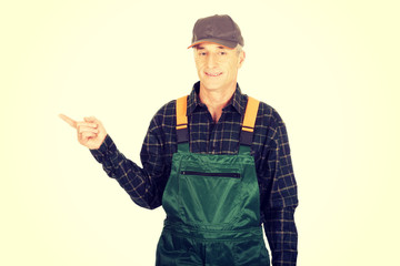 Mature gardener in uniform pointing to the left
