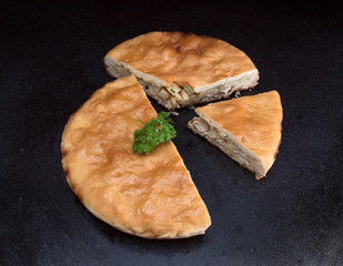 Chicken and potato pie with a segment cut out against black marble background © yarlander