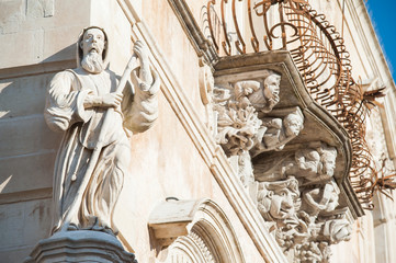 The baroque statue of St. Francis of Paola sculpted at the corner of Cosentini palace in Ragusa Ibla with some mascarons under its balconies