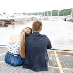 A couple walks along the pier boats at sea in sunny weather