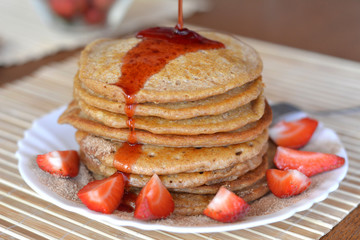 Stack of sweet pancakes with strawberries and syrup