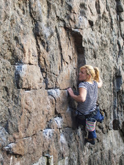 Young woman with rope climbs on the rock.