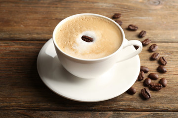 Cup of latte art coffee with grains on wooden background