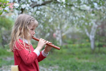 White girl in a red sundress, playing the flute on a green background © rimm7616