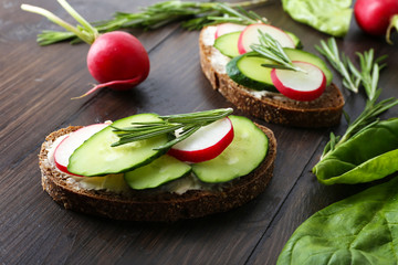 Delicious sandwiches with vegetables and greens on table close up