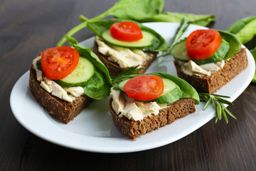 Delicious sandwiches with vegetables and greens on plate close up
