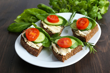 Delicious sandwiches with vegetables and greens on plate close up