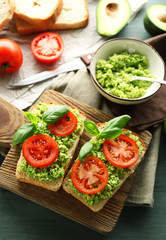 Fototapeta na wymiar Vegan sandwich with avocado and vegetables on cutting board, on wooden background