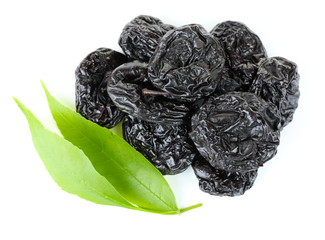 Pile of prunes with green leaves isolated on white