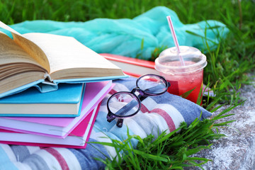 Books, glasses and drink on grass close-up