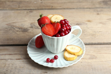 Cup of dessert with fresh fruits on wooden table, closeup