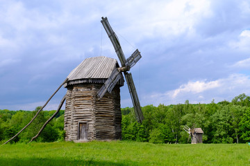 Fototapeta na wymiar Old wooden windmills on green field, on blue sky background