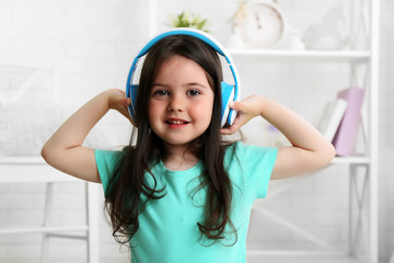 Beautiful little girl listening to music in room