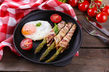 Dish of asparagus with eggs and bacon in pan on table, closeup