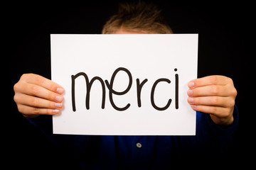 Child holding sign with French word Merci - Thank You