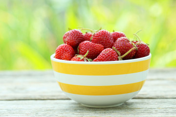 Strawberries berry in bowl on grey wooden background
