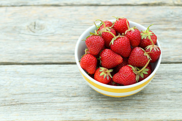 Strawberries berry in bowl on grey wooden background