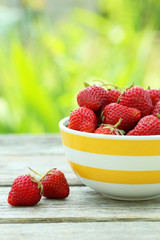 Strawberries berry in bowl on grey wooden background