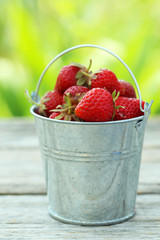 Strawberries berry in bucket on grey wooden background