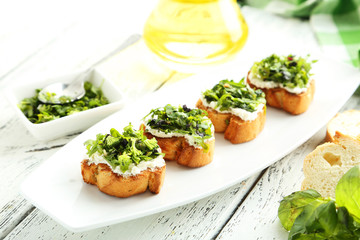 Tasty fresh bruschetta on plate on white wooden background