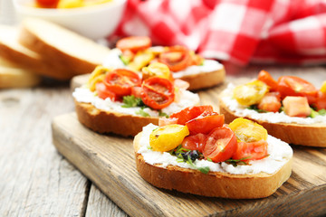 Tasty fresh bruschetta with tomatoes on cutting board on grey wo