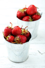 Strawberries berry in bucket on white wooden background