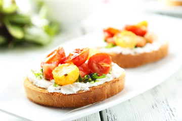 Tasty fresh bruschetta with tomatoes on plate on white wooden ba