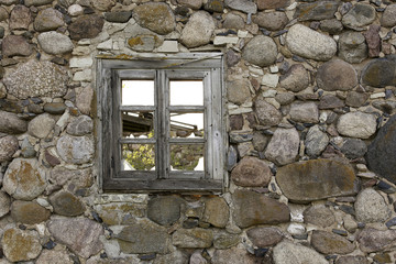 An old empty wooden window in a stone wall