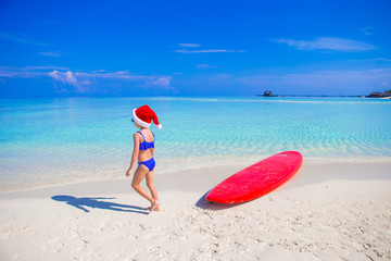 Naklejka na ściany i meble Little girl in Santa hat on the beach during vacation