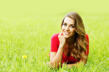 young woman in red dress lying on grass