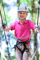 Happy child, healthy teenage school boy enjoying activity in a climbing adventure park on a summer day