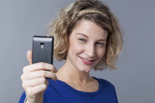 Beautiful 20s woman smiling for selfshot or selfie portrait on telephone