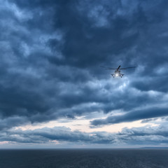 Fototapeta na wymiar Storm at sea, Mi-8 helicopter from below in front dramatic sky,