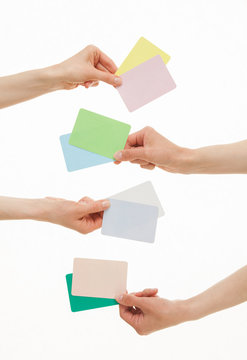 Four hands holding colorful paper cards