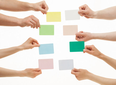 Many hands holding colorful paper cards