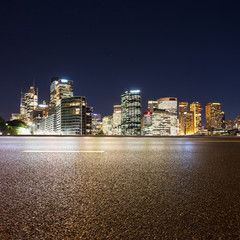 Fototapeta premium Empty asphalt road and illuminated modern cityscape background a